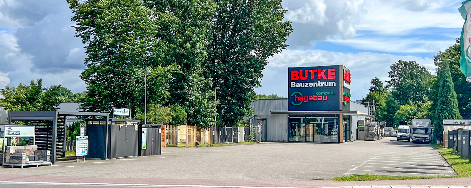 Aufnahme des Baumarkts von der Straße aus. Im Zentrum der Eingangsbereich mit den Logos Butke Bauzentrum und Hagebau kompakt Aufnahme des Baumarkts von der Straße aus. Im Zentrum der Eingangsbereich mit den Logos Butke Bauzentrum und Hagebau kompakt